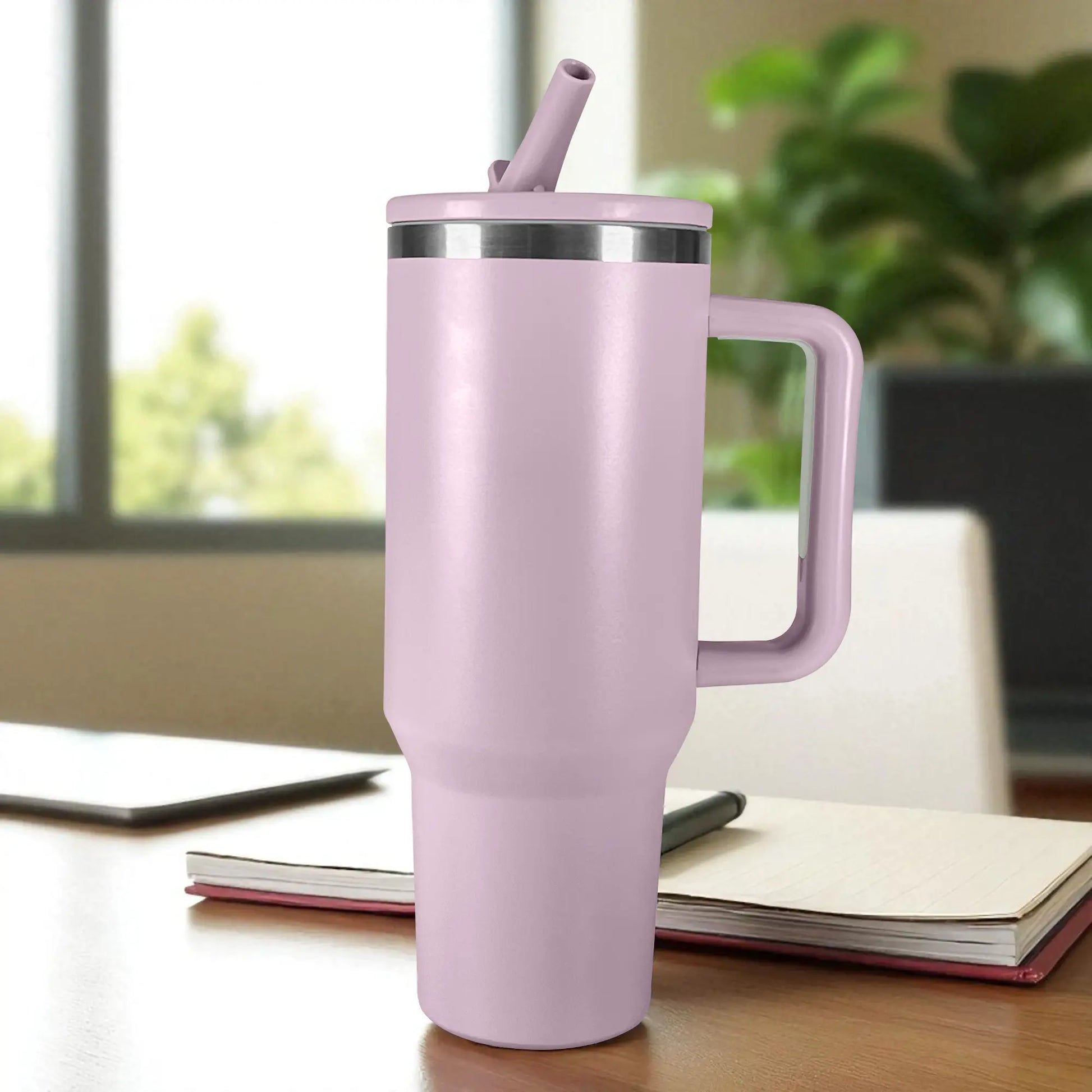 Vaso térmico de acero inoxidable color morado lila de 1200 ml con tapa y popote reutilizable, colocado en escritorio junto a cuaderno.