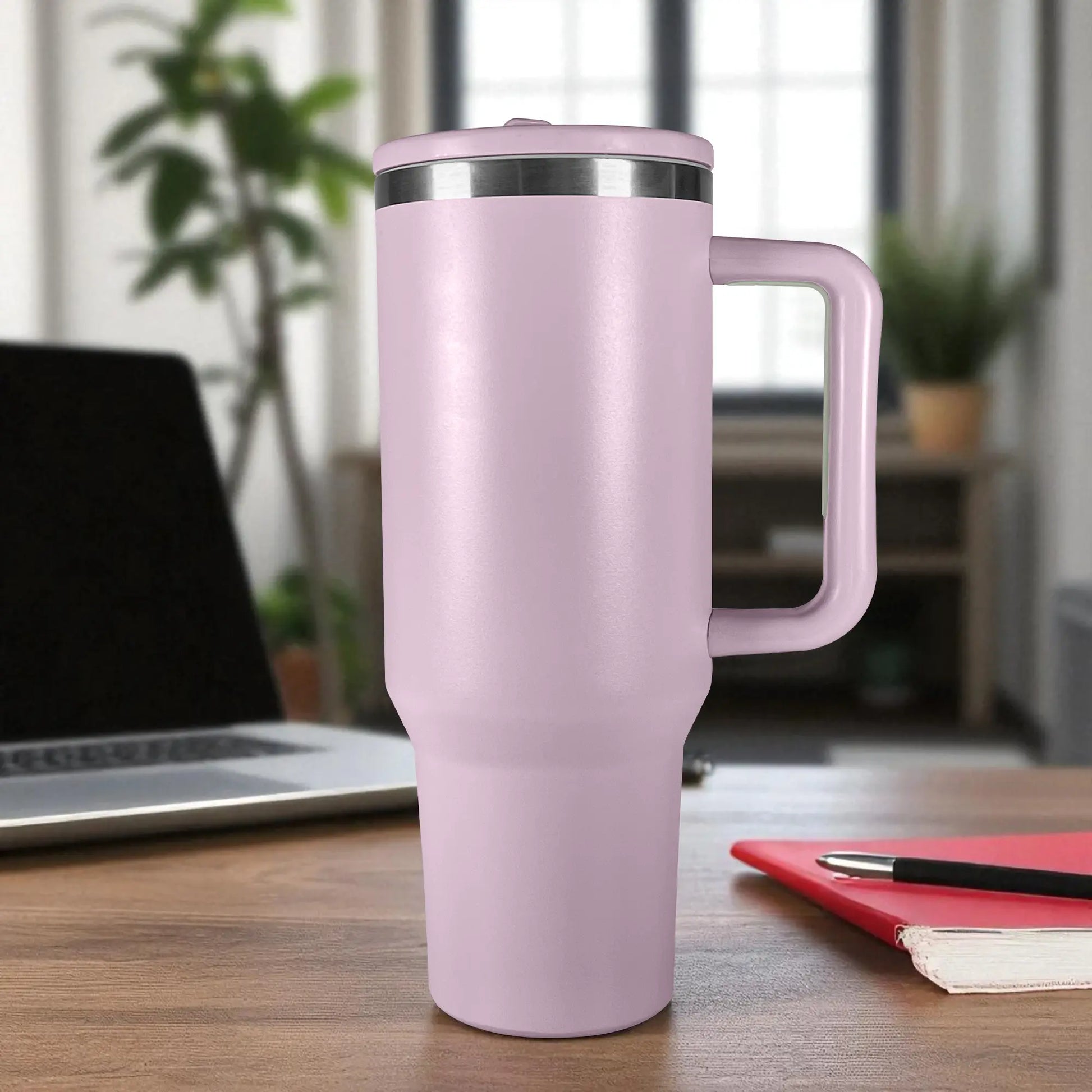 Vaso térmico grande de acero inoxidable color morado lila de 1200 ml con tapa y asa, sobre mesa de oficina con laptop al fondo.